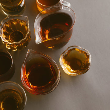 Glass containers filled with tea on a gray surface